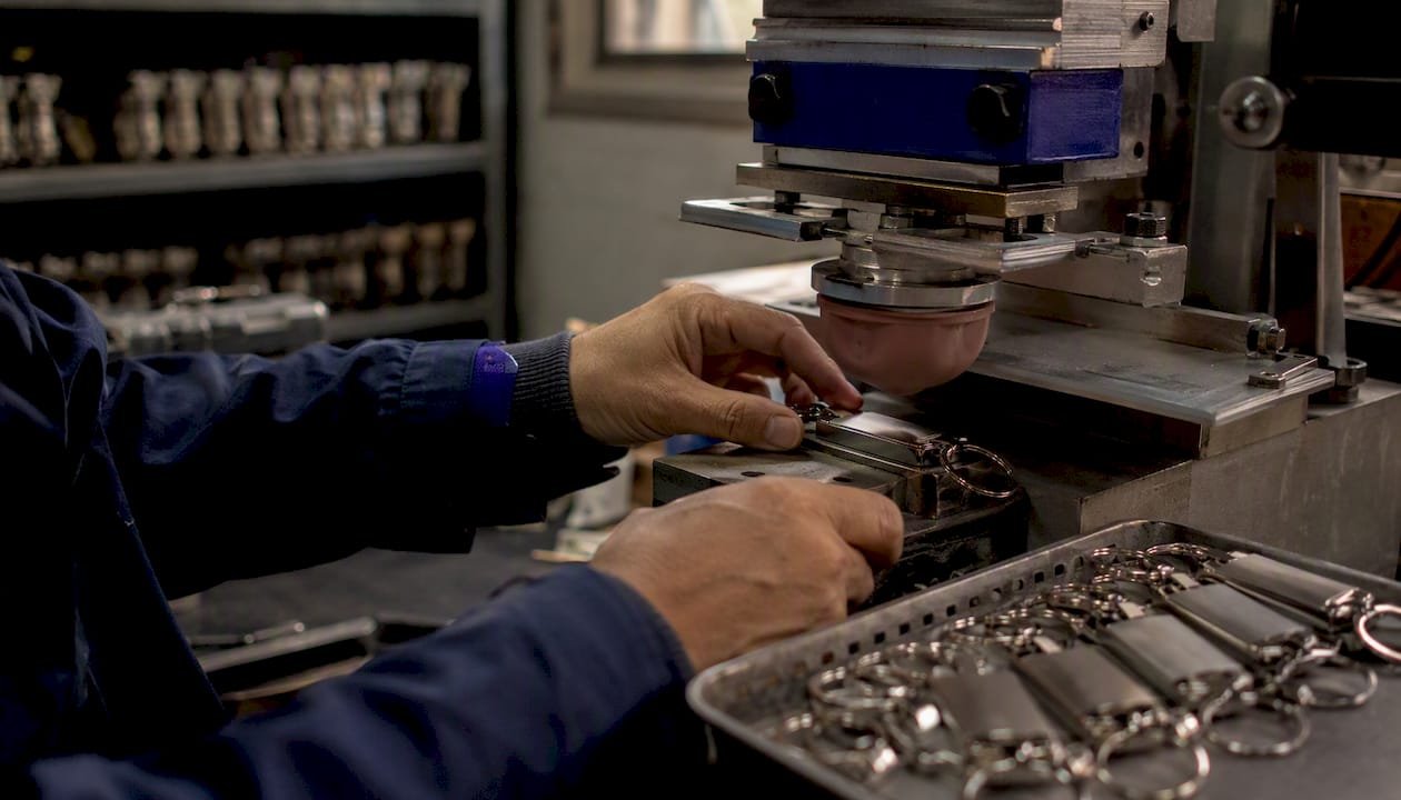 Technician applying pad printing to keychain