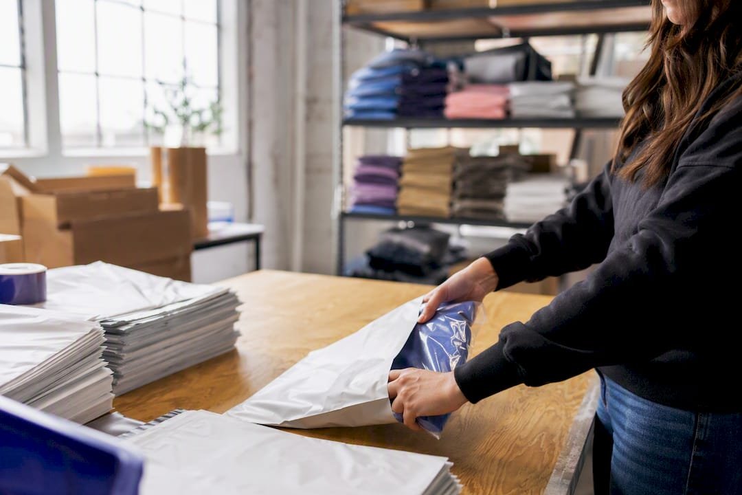 Hands packing corporate gift into poly mailer